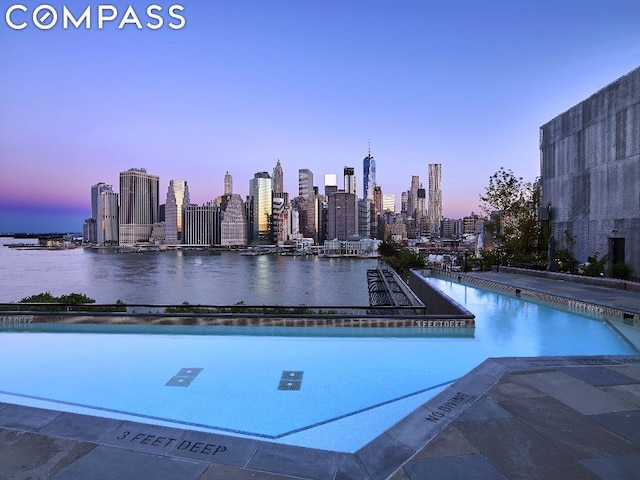 pool at dusk featuring a water view