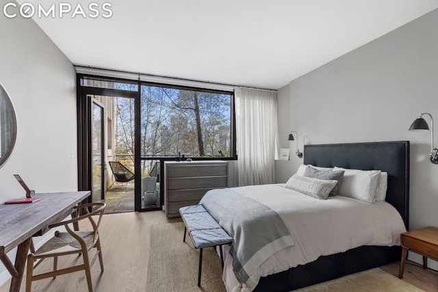 bedroom with floor to ceiling windows and light hardwood / wood-style floors