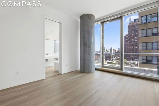 empty room featuring floor to ceiling windows and light hardwood / wood-style flooring