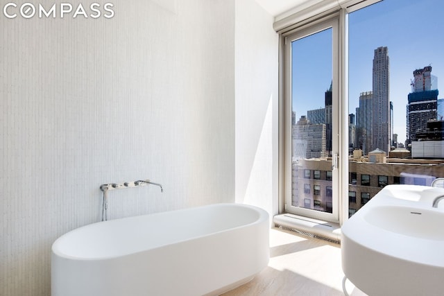 bathroom featuring a bath, a healthy amount of sunlight, and a wall of windows