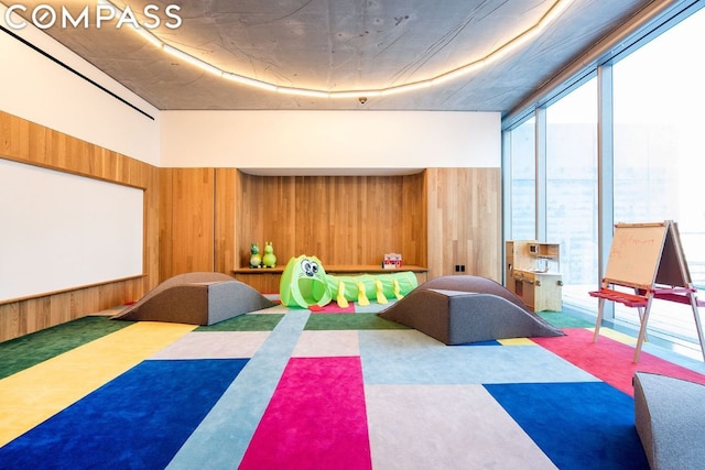 recreation room with carpet and wood walls