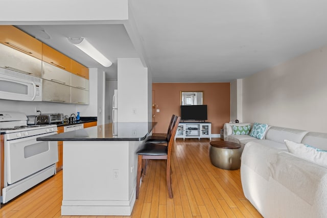 kitchen with a breakfast bar, light wood-type flooring, and white appliances