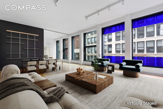 living area with track lighting, floor to ceiling windows, and wood finished floors