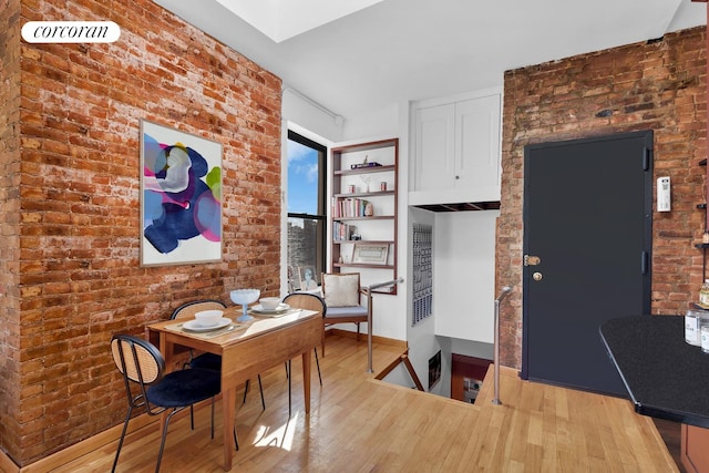 dining area featuring visible vents, baseboards, wood finished floors, and brick wall