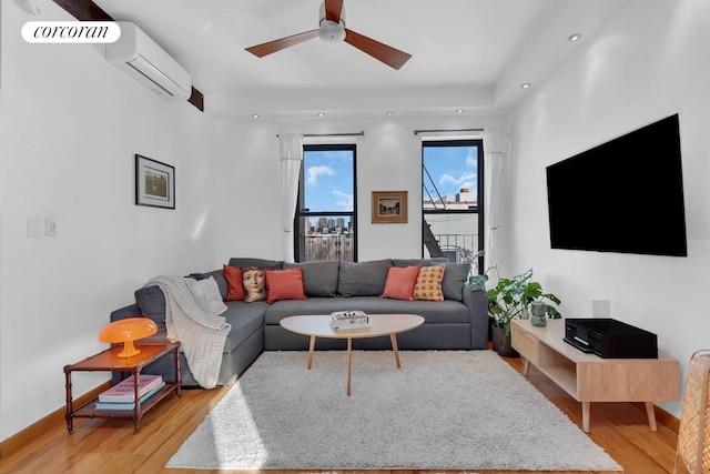 living area with a ceiling fan, baseboards, recessed lighting, a wall unit AC, and light wood-type flooring