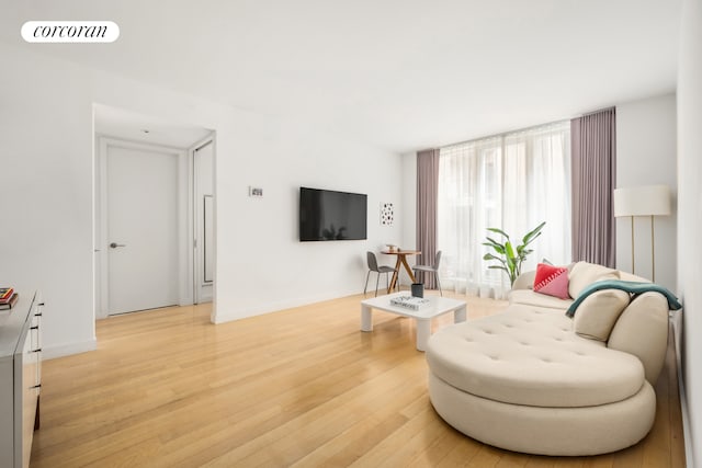 living area with light wood-style flooring, visible vents, and baseboards