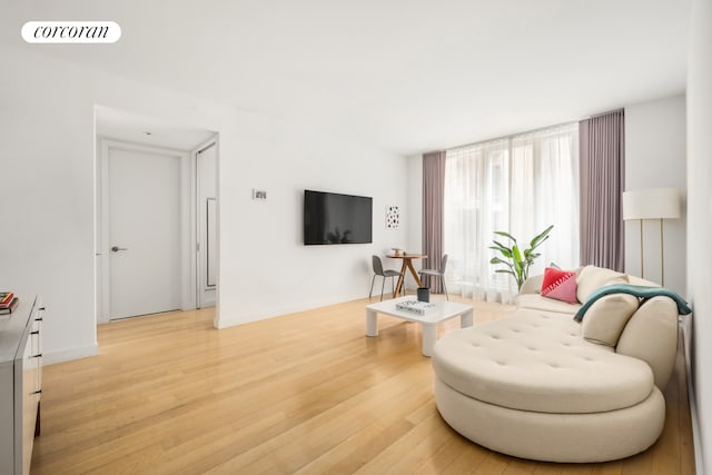 living room with light wood-style floors, baseboards, and visible vents