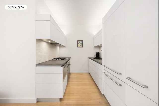 kitchen with white cabinets, dark countertops, modern cabinets, and light wood-style floors