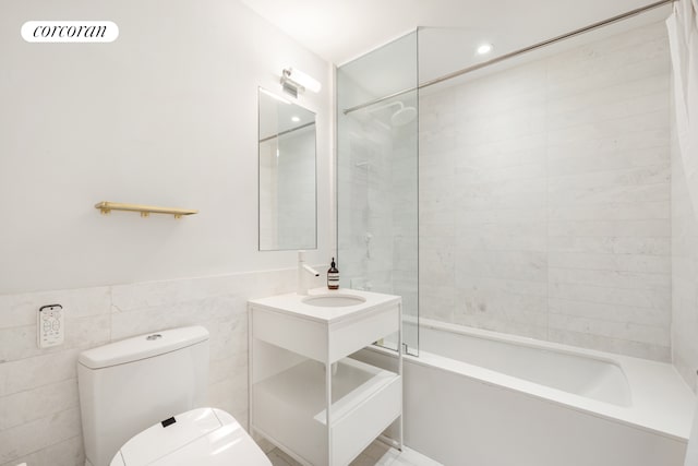 bathroom with vanity, toilet, a wainscoted wall, tile walls, and bathing tub / shower combination