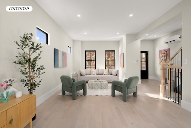 living room with a wall unit AC and light hardwood / wood-style flooring