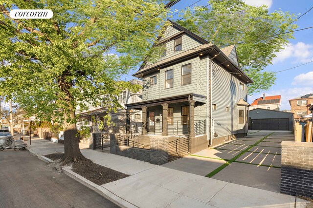 view of front facade with a garage, an outbuilding, and covered porch