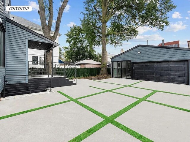 view of patio / terrace with concrete driveway, fence, and a garage