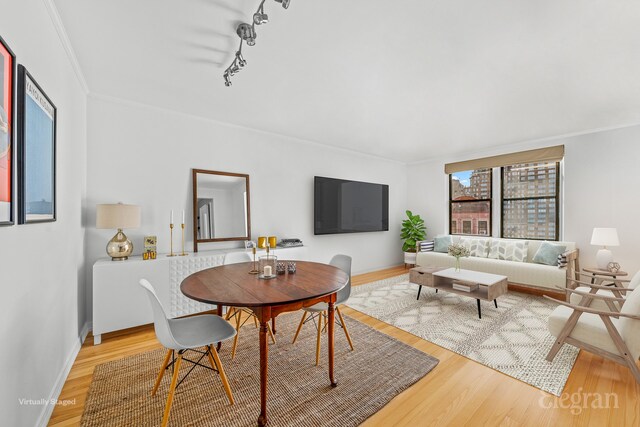 dining space featuring ornamental molding, light hardwood / wood-style floors, and rail lighting