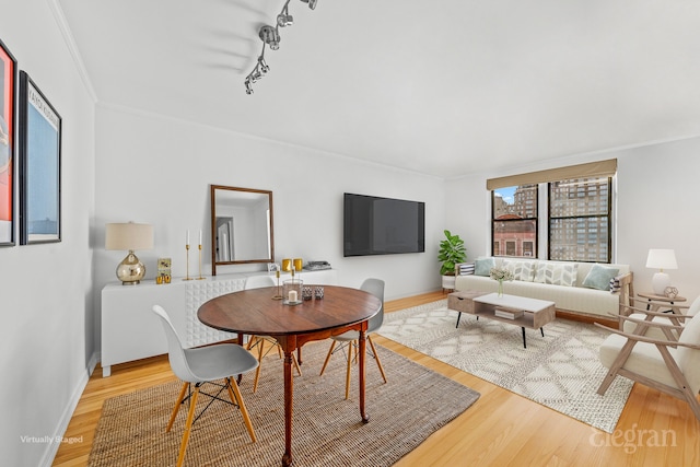 dining area featuring track lighting, baseboards, light wood-style floors, and ornamental molding