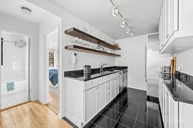 kitchen with stainless steel dishwasher, dark wood-type flooring, sink, and white cabinetry