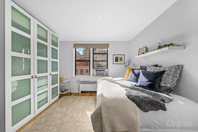 bedroom featuring radiator, cooling unit, and light hardwood / wood-style flooring