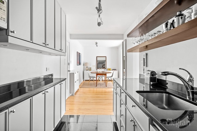 kitchen with light tile patterned floors, white cabinets, and sink