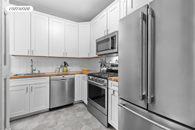 kitchen with wood counters, appliances with stainless steel finishes, and white cabinets