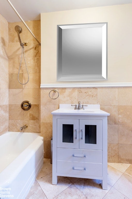 bathroom featuring tile walls, vanity, and tiled shower / bath combo