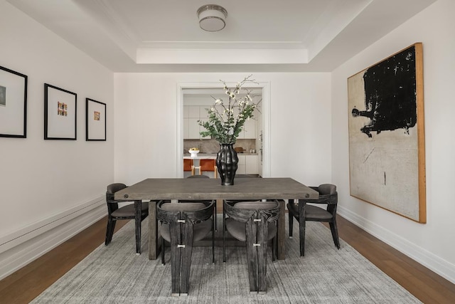 dining area with hardwood / wood-style flooring and a raised ceiling