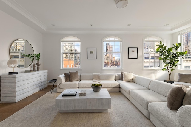 living room featuring light wood-style flooring, ornamental molding, a raised ceiling, and a wealth of natural light