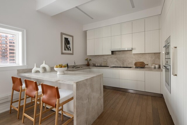 320 E 82nd Street Penthouse, New York City, NY 10028 - kitchen with modern cabinets, a sink, a kitchen bar, and dark wood-style floors
