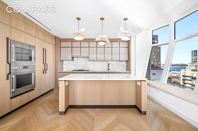 kitchen with tasteful backsplash, modern cabinets, a center island, gas cooktop, and a sink