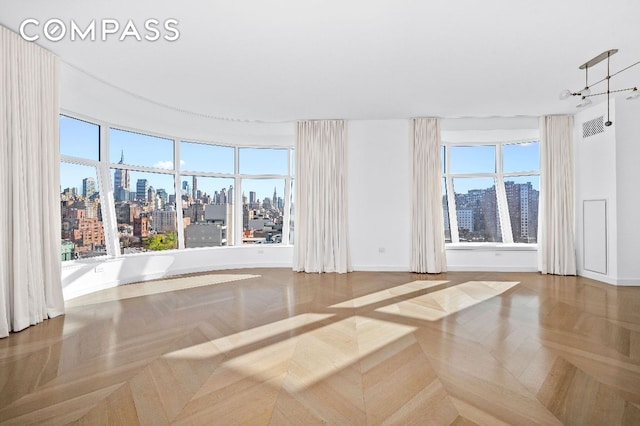 spare room with baseboards, visible vents, and a city view