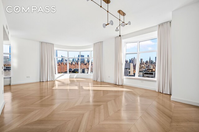 unfurnished room with light parquet flooring and an inviting chandelier