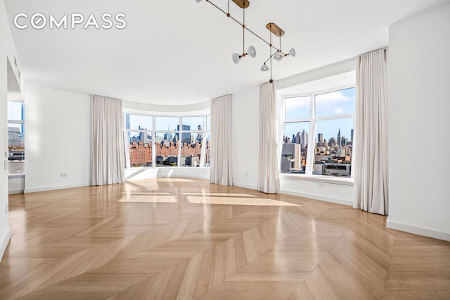 interior space featuring baseboards, a view of city, and a chandelier