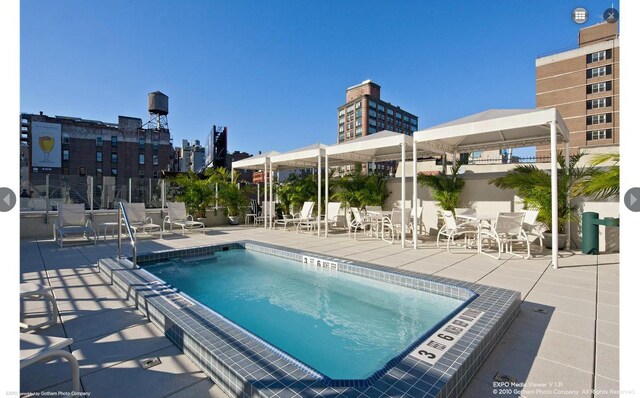 view of pool featuring a patio, a view of city, and fence