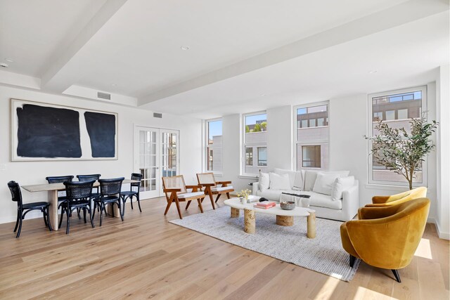 living room with beamed ceiling, light hardwood / wood-style floors, and french doors