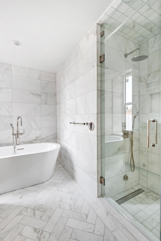 bathroom featuring tile walls, a soaking tub, a stall shower, and marble finish floor