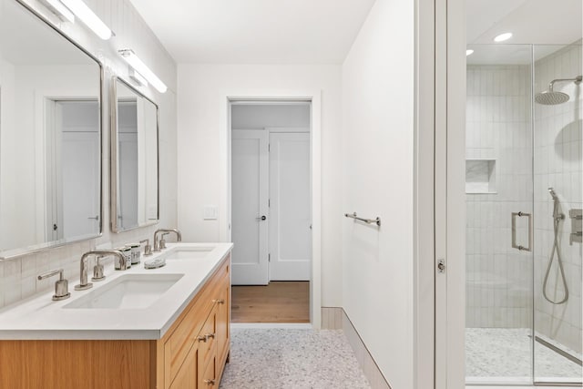 full bath with a shower stall, recessed lighting, double vanity, and baseboards