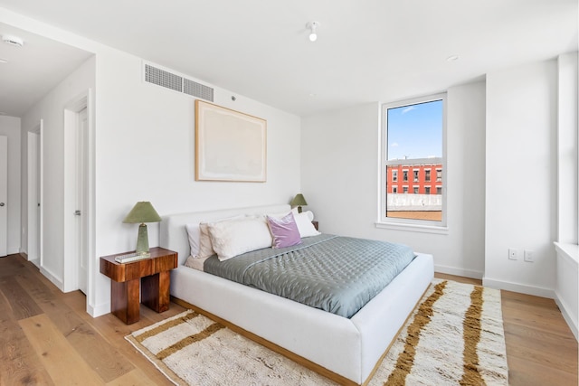 bedroom with baseboards, visible vents, and light wood finished floors