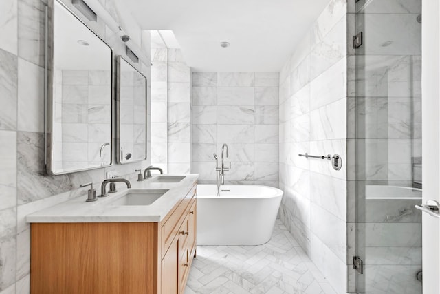 bathroom with double vanity, a soaking tub, tile walls, and a sink