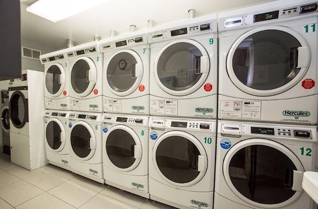 washroom with stacked washer and dryer, washing machine and dryer, and light tile patterned floors