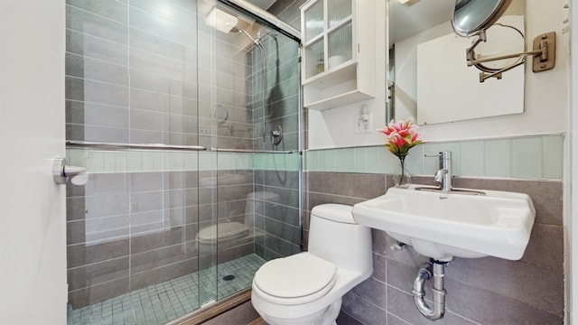 bathroom with toilet, a shower with shower door, sink, and tile walls