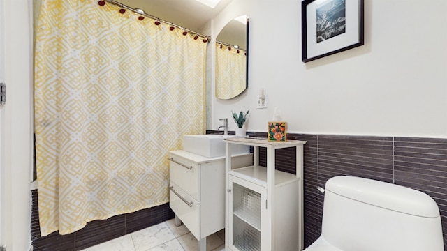 bathroom with vanity, tile walls, and toilet