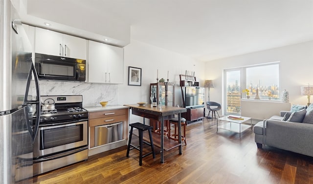 kitchen featuring white cabinetry, backsplash, dark wood-type flooring, and stainless steel appliances