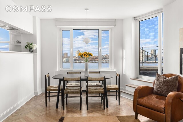 dining area featuring a water view and light parquet floors