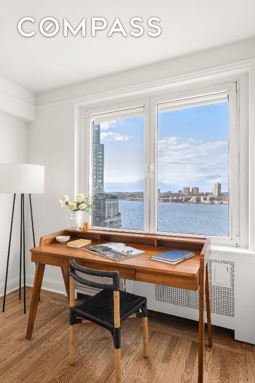 dining room with radiator heating unit, wood-type flooring, and a water view