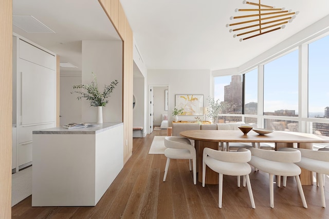 dining room featuring a wall of windows, a view of city, and wood finished floors