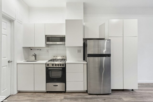 kitchen with stainless steel appliances, backsplash, white cabinetry, and sink