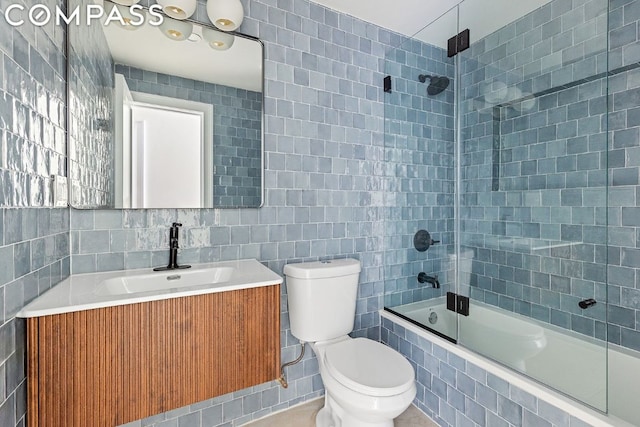 full bathroom featuring bath / shower combo with glass door, tile walls, toilet, and vanity