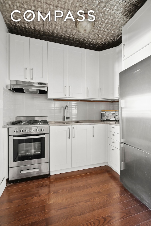 kitchen featuring tasteful backsplash, under cabinet range hood, an ornate ceiling, stainless steel appliances, and a sink