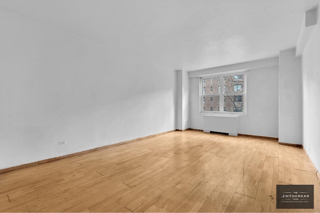 empty room featuring radiator and light hardwood / wood-style floors