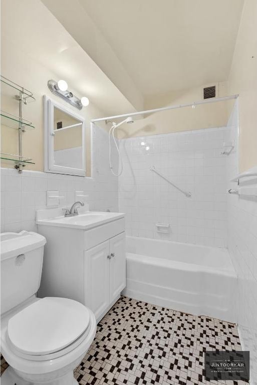 full bathroom with tiled shower / bath combo, vanity, tile walls, and toilet