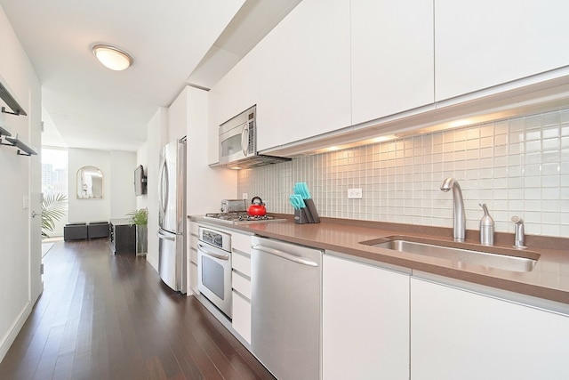 kitchen with stainless steel appliances, white cabinetry, sink, and backsplash