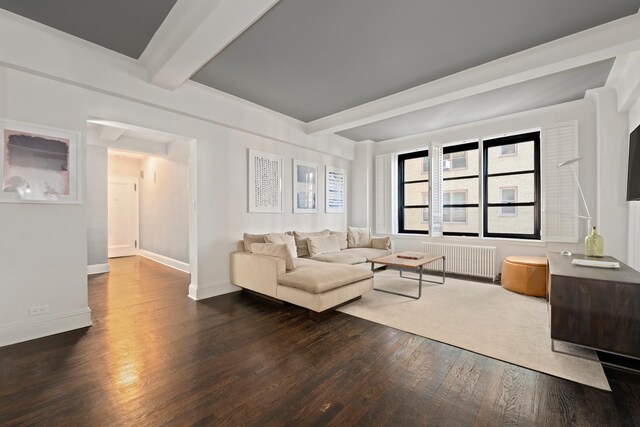 living room with radiator heating unit, beam ceiling, and dark hardwood / wood-style flooring